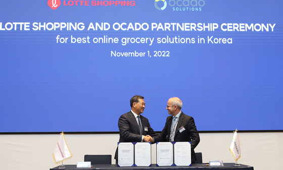 Kim Sang-hyun, CEO of Lotte Shopping, left, shakes hands with Ocado Group CEO Tim Steiner after celebrating the signing of an exclusive partnership agreement on Tuesday. [LOTTE SHOPPING]