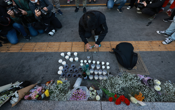 Los visitantes lloran a las víctimas de la aglomeración del sábado en Itaewon, en el centro de Seúl, en un espacio conmemorativo frente a la salida 1 de la estación de Itaewon el domingo.  [YONHAP]