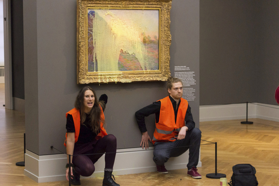 Climate protesters of Last Generation after throwing mashed potatoes at the Claude Monet painting ″Les Meules” at Potsdam’s Barberini Museum on Sunday Oct. 24, 2022, to protest fossil fuel extraction. (Last Generation via AP)