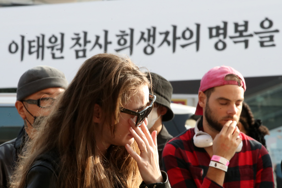 Foreign students mourn those killed in the Itaewon crowd crush at the makeshift memorial in front of Exit No. 1 at Itaewon Station, Yongsan District, Seoul on Tuesday. [NEWS1]