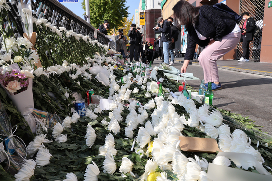 A mourner places flowers at Exit No. 1 of Itaewon Station on Monday. [WOO SANG-JO]