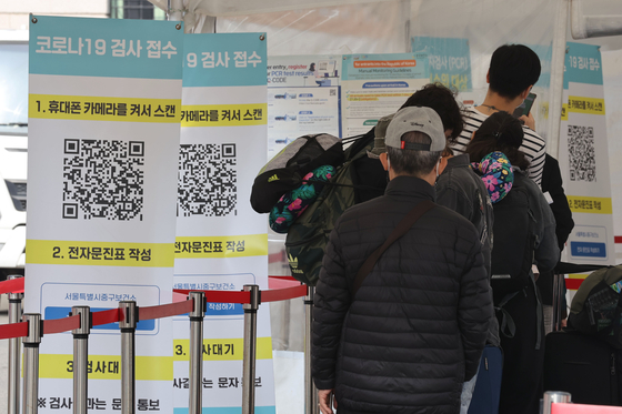 People stand in line to get tested for Covid-19 at a testing center in Seoul Station on Monday. [NEWS1] 