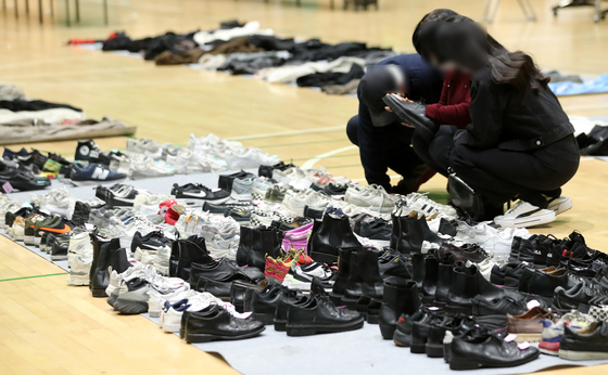 Relatives of people killed in Itaewon last Saturday search for shoes recovered from the scene of the tragedy in a center set up in a gymnasium in Yongsan District, central Seoul, on Wednesday. [NEWS1]