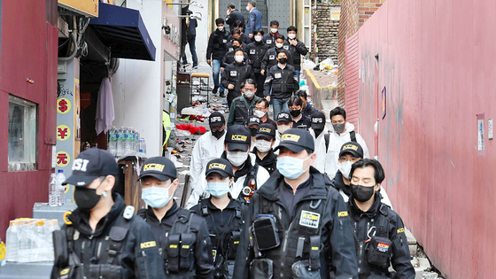 Police and forensics teams walk out of the alleyway in Itaewon where most of the 156 casulaties were found on Sunday. [WOO SANG-JO]