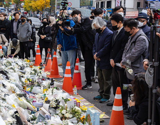 Liberal activists pay respects at a makeshift memorial altar for the victims of the Itaewon tragedy near Itaewon Station in Yongsan District, central Seoul, on Thursday. They announced plans to hold a candlelight vigil to commemorate the victims on Saturday. [YONHAP] 