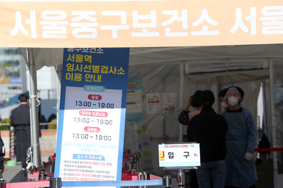 People stand in line to get tested for Covid-19 at a testing center near Seoul Station on Wednesday. [NEWS1] 