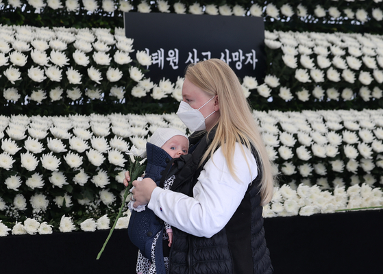 A foreign national with a baby pays tribute to victims of the Halloween crowd crush at a memorial altar in Itaewon on Nov. 1. [YONHAP]
