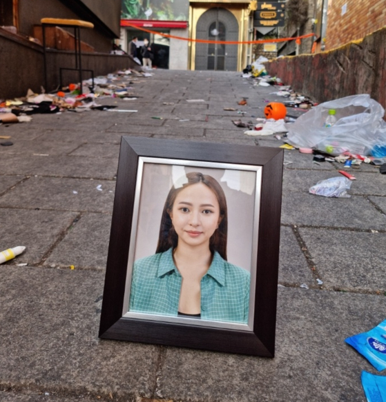 A photo of Yuliana Pak, one of the four Russian victims of the Itaewon tragedy, is placed on the site of the crowd crush in Itaewon, central Seoul, on Tuesday. [YULIANA PAK'S FAMILY]
