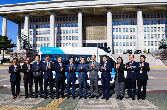 Officials from the National Assembly and Hyundai Motor, including President Kong Young-woon, sixth from left, and Lee Kwang-jae, seventh from left, secretary general of the National Assembly, take a photo with Hyundai's RoboShuttle Friday. [HYUNDAI MOTOR]