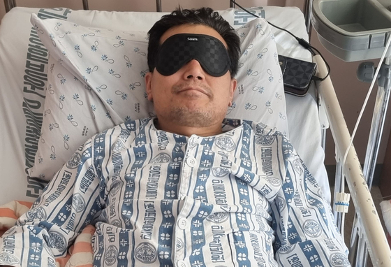 A 62 year-old miner rescued from a collapsed vertical mine shaft on Friday rests in bed at a hospital in Andong, North Gyeongsang on Friday. He wears an eye mask to protect his sight after his prolonged ordeal underground. [YONHAP]