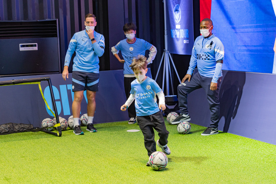 Shaun Wright-Phillips, right, watches a young Manchester City fan play the ball on Sunday at SJ Kunsthalle in Gangnam District, southern Seoul. [MANCHESTER CITY FOOTBALL CLUB]