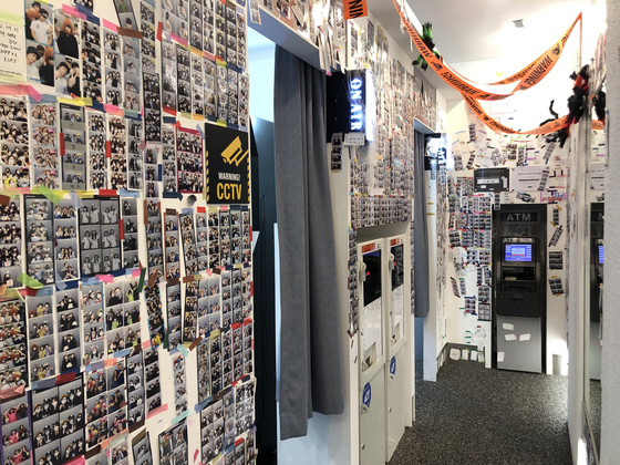The inside of a Photoism store in Seo District, Incheon shows two photo booths and hundreds of photo strips taped onto the walls. [SHIN MIN-HEE]