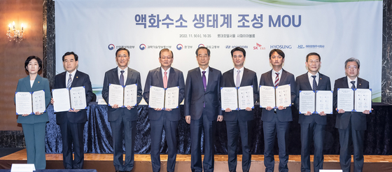 Prime Minister Han Duck-soo, fifth from left, poses for a photo with representatives from the Ministry of Environment, the Ministry of Trade, Industry and Energy, Hyundai Motor, Hyosung, SK E&S, Hychangwon, the Ministry of Science and ICT, and the Ministry of Land, Infrastructure and Transport, during a signing ceremony held Wednesday in central Seoul. [SK E&S]