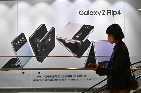 A woman walks past an advertisement for the Samsung Galaxy Z Flip 4 smartphone at the company's Seocho building in Seoul. [AFP]
