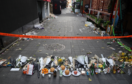 Flowers to pay respect to the victims of the Itaewon tragedy are laid in front of the police's access restriction line near the incident site on Monday. [YONHAP] 