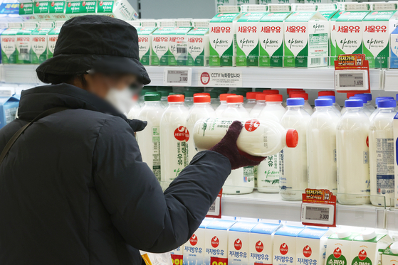A customer purchases a bottle of milk at a discount mart in Seoul on Nov. 4. [YONHAP] 