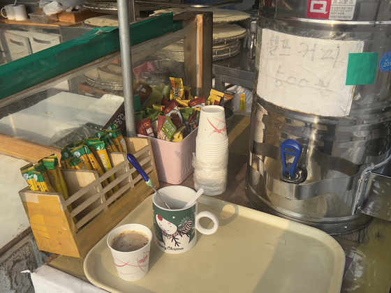 A food stall at Dongmyo Flea Market sells instant coffee mixes for 500 won a cup, with customers making their own cup of coffee. [LEE TAE-HEE]