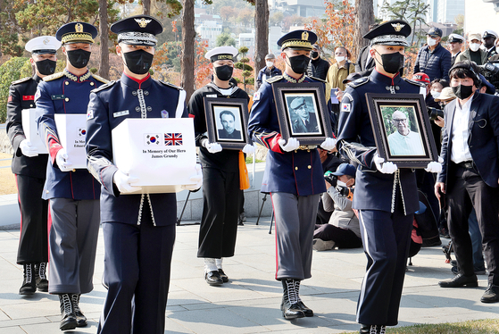 A Korean honor guard carries the ashes and portraits of Korean War (1950-53) veterans James Grundy of Britain and Mathias Hubertus Hoogenboom and Eduard Julius Engberink of the Netherlands to the graveyard at UN Memorial Park in Busan on Friday. The three Korean War veterans, who passed away recently, requested to be buried at the graveyard in Korea. [SONG BONG-GEUN]