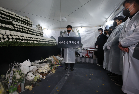 Officials pay tribute to the victims of the Itaewon crowd crush before demolishing the memorial altar set up near Noksapyeong Station in Yongsan District, central Seoul, on Sunday. [YONHAP]