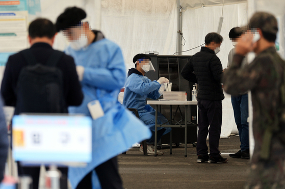 Health workers guide people at a Covid-19 testing center in front of Seoul Station in Jung District, central Seoul, on Sunday. [YONHAP]
