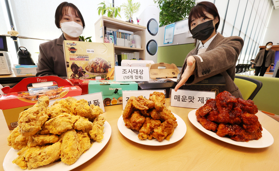 Korea Consumer Agency officials display Korean marinated fried chicken of leading franchises at the government complex in Sejong on Tuesday. The consumer agency released information including the retail prices and nutritional information. [YONHAP] 