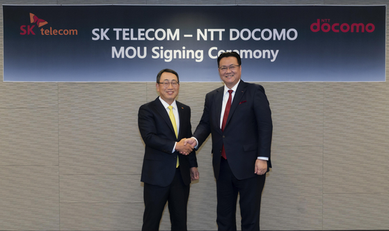 SK Telecom CEO Ryu Young-sang, left, and NTT Docomo President Ii Motoyuki pose for a photo during a signing ceremony on Friday at the Grand Walkerhill Hotel in eastern Seoul. [SK TELECOM]