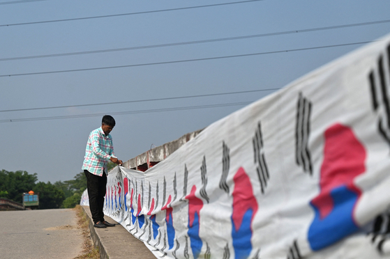 Abu Kowsir hangs a 3.5-kilometer (2.2-mile) Korean flag on a bridge near his home in Bancharampur, Bangladesh on Nov. 16.  [AFP/YONHAP]