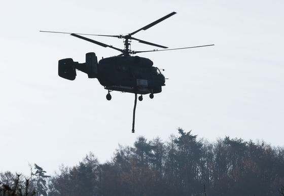 A helicopter on Monday flies over a mountainous area in Yangpyeong, Gyeonggi, near where a KF-16 fighter jet crashed after suffering an engine malfunction on Sunday. [YONHAP]