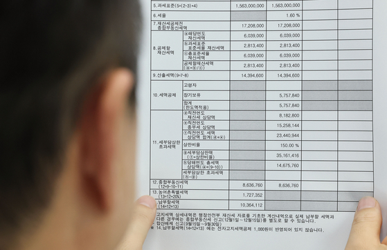 A person looks at a bill for the comprehensive real estate holding tax on Monday, which was sent starting the same day. An estimated 1.2 million people will be getting bills this year for the comprehensive real estate holding tax, which is the first time more than 1 million people have been charged.[YONHAP] 