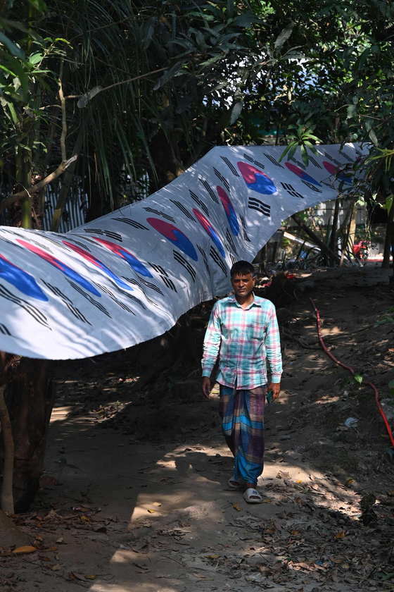 Bangladeshi chemist Abu Kowsir walks past his flag in Bancharampur, Bangladesh on Nov. 16.  [AFP/YONHAP] 