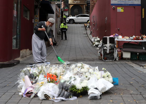 A volunteer cleans up a makeshift memorial space for the victims of the Itaewon crowd crush at Exit 1 of Itaewon Station in Yongsan District, central Seoul, on Nov. 13. [NEWS1]
