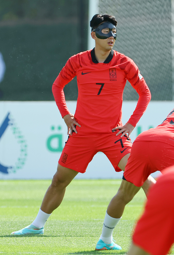 Son Heung-min wears a mask to protect the healing fracture during the Korean national team training session on Wednesday at Al Egla Training Facility, Doha, Qatar. [JOONANG ILBO]