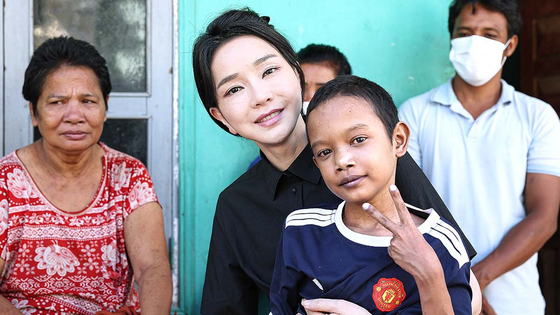 First lady Kim Keon-hee takes a photo with a 14-year-old boy suffering from congenital heart disease at his home in Phnom Penh, Cambodia on Saturday. She visited a local medical center twice during the trip to Cambodia to discuss ways to treat the boy. [PRESIDENTIAL OFFICE] 