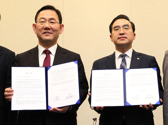 Floor leader of the People Power Party Joo Ho-young, left, and floor leader of the Democratic Party Park Hong-keun, right, stand with signed agreements on initiating a parliamentary probe into the Itaewon crowd crush during a press briefing at the National Assembly in Yeouido, western Seoul, on Wednesday. [YONHAP]