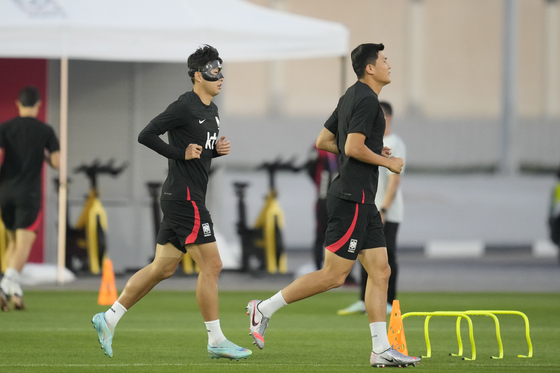 Son Heung-min, left, and Kim Min-jae warm up during a training session at Al Egla Training Site in Doha, Qatar on Tuesday. Korea will play its first match against Uruguay on Thursday. [AP/YONHAP]