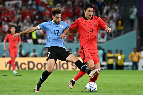Cho Gue-sung, right, fights for the goal against Uruguay's defender Matias Vina during a 2022 Qatar World Cup Group H match between Uruguay and Korea at Education City Stadium in Al-Rayyan, west of Doha on Thursday. [AFP/YONHAP]