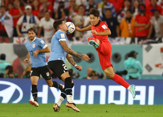 Korea's Lee Kang-in, right, in action with Uruguay's Jose Maria Gimenez during a Group H game at the 2022 Qatar World Cup at Education City Stadium in Qatar on Thursday.  [REUTERS/YONHAP]