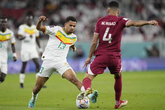Senegal's Ismail Jakobs, left, and Qatar's Mohammed Waad battle for the ball during the World Cup group A soccer match between Qatar and Senegal, at the Al Thumama Stadium in Doha, Qatar on Friday. Senegal beat the hosts 3-1 to mark Qatar's second loss in a row after Eqaudor beat them 2-0 on Monday. [AP/YONHAP]