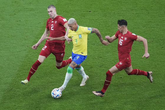 Brazil's Richarlison, center, is challenged by Serbia's Strahinja Pavlovic, left, and Sasa Lukic during the World Cup group G football match between Brazil and Serbia, at the the Lusail Stadium in Lusail, Qatar on Thursday. Brazil beat Serbia 2-0 with Richarlison scoring both goals in the second half of the match. [AP/YONHAP]