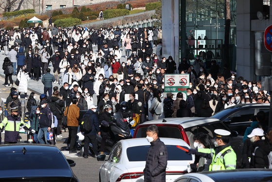 Police stand by as college hopefuls pour out of Ewha Womans University in Seodaemun District, western Seoul, after taking essay tests on Sunday. Students took the national College Scholastic Ability Test (CSAT) on Nov. 17. [YONHAP]
