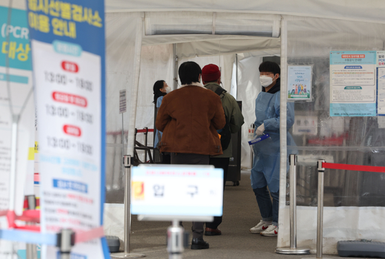 People stand in line to get tested for Covid-19 at a center near Seoul Station on Sunday. [YONHAP] 