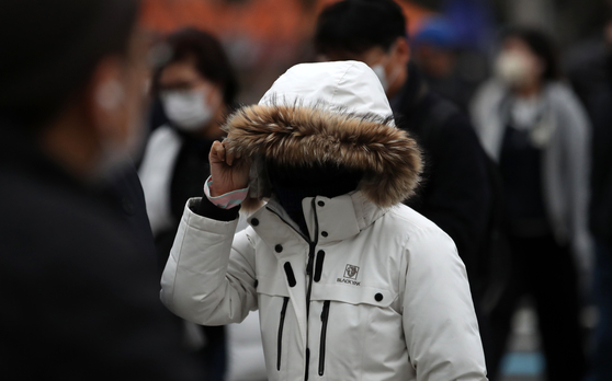 A person wearing a thick coat walks in downtown Seoul on Tuesday as the country's temperatures started to drop. [NEWS1]