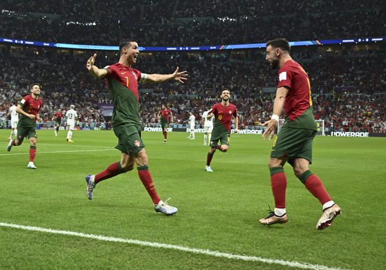 Bruno Fernandes of Portugal, right, celebrates his goal with teammate Cristiano Ronaldo during the Group H match between Portugal and Uruguay at the 2022 FIFA World Cup at Lusail Stadium in Lusail in Qatar on Monday. A double from Fernandes shut out Uruguay 2-0 and earned Portugal a seat in the knock out round. [XINHUA/YONHAP]