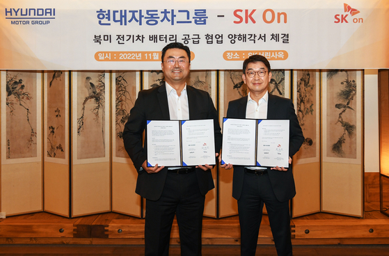 Kim Heung-soo, left, head of the corporate future growth planning division at Hyundai Motor, and Choi Young-chan, chief administrative officer at SK On, take a photo after signing a battery supply agreement on Tuesday at SK headquarters in central Seoul. [HYUNDAI MOTOR]