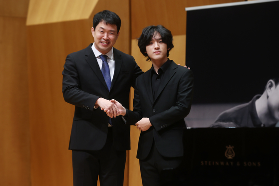 Pianist Lim, right, and conductor Hong Seok-won of the Gwangju Symphony Orchestra shake hands during a press conference held on Monday. [NEWS1] 