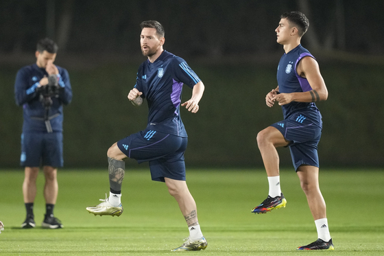 Lionel Messi, left, and Paulo Dybala of Argentina warm up during a training of Argentina on the eve of a group C World Cup football match against Poland in Doha, Qatar on Tuesday. [AP/YONHAP]