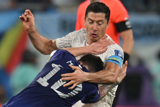 Argentina's forward Lionel Messi, front, and Poland's forward Robert Lewandowski fight for the ball during the Qatar 2022 World Cup Group C football match between Poland and Argentina at Stadium 974 in Doha on Wednesday. [AFP/YONHAP]