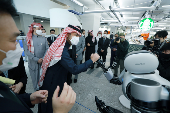 Al-Hogail shakes hands with a Naver robot. [NAVER]