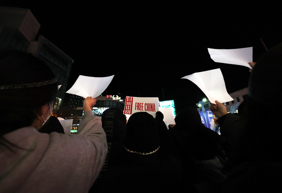 Protesters hold up blank sheets of paper and slogans during a protest at Hongdae, Mapo District, western Seoul on Wednesday night. [YONHAP]