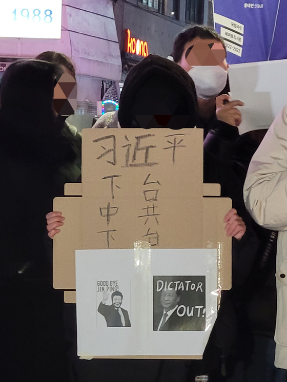 A protester holds up a picket saying ″Dictator Out!" over a picture of Chinese President Xi Jinping at Hongdae, Mapo District, western Seoul on Wednesday night. [KIM NAM-YOUNG]